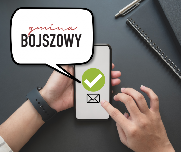 elefon w dłoni z ikoną wiadomości i zielonym znacznikiem, obok grafika z napisem "gmina Bojszowy"